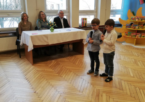 dwóch chłopców i dorośli za biurkiem