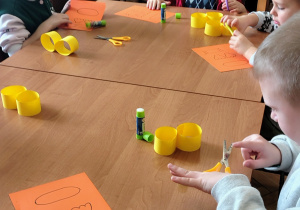 przedszkolaki przy stole, kartki, kształty z papieru