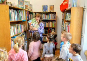 sala biblioteczna, regały z książkami, dzieci, kobieta z książką w ręku
