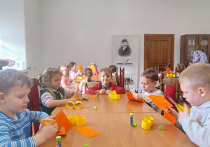 przedszkolaki przy stole, kartki, kształty z papieru
