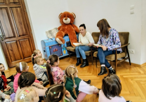 sala biblioteczna, przedszkolaki, duży pluszowy miś, 2 biblotekarki