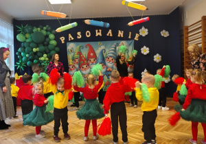 grupa tańczących przedszkolaków, osoby dorosłe, dekoracja w tle