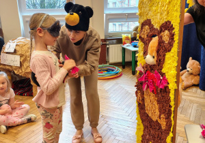 kobiety w czpkach misia, dziewczynka z opaską na oczach, makieta misia