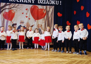 grupka przedszkolaków, eleganckie stroje, w tle baner dekoracyjny