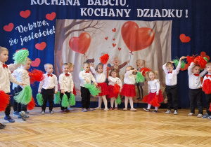 grupka przedszkolaków, eleganckie stroje, pompony,w tle baner dekoracyjny