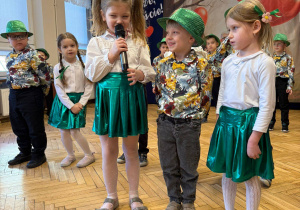 przedszkolaki w strojach, kapeluszach z mikrofonem w rękach