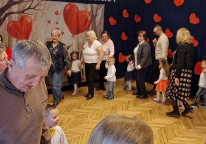 pzredszkolaki tańczące w kółku z dziadkami i babciami