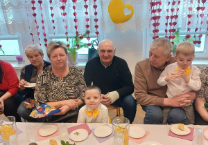 przedszkolaki, babcie, dziadkowie za stołem z poczęstunkiem