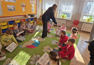 sala przedszkolna, przedszkolaki, uczennica rozdająca obrazki