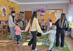 sala przedszkolna, przedszkolaki tańczące w kole z licealistakami