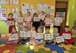 sala przedszkolna, grupa przedszkolaków z obrazkami w rękach