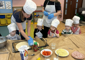 nauczycielki, przedszkolaki w czapkach kucharskich, ciasto na pizzę, składniki na pizzę