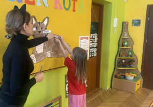 nauczycielka w przebraniu kota, dziewczynka przypinająca nazwę części ciała kota na obrazek kota