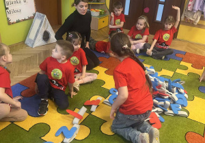 nauczycielka w przebraniu kota, przedszkolaki w czerwonych koszulkach, układanie wyrazu z liter