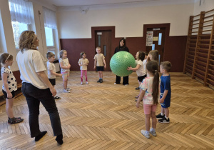 sala gimnastyczna, przedszkolaki, duża piłka, 2 osoby dorosłe