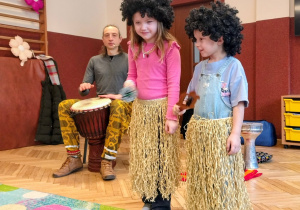 muzyk z bębnem afrykańskim, dwoje dzieci w stroju afrykańskim i peruce