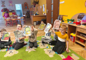 przedszkolaki z obrazkami plecaków w rękach