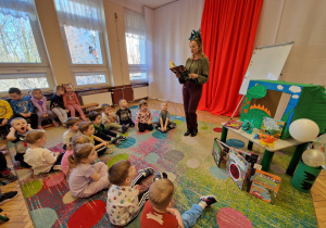 grupa przedszkolaków, pani czytająca książkę
