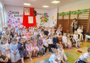 grupa przedszkolaków, nauczycielki, w tle dekoracja z okazji 8 marca