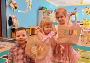 sala przedszkolna, chłopiec, 2 dziewczynki z torebkami z napisem "sun" w rękach