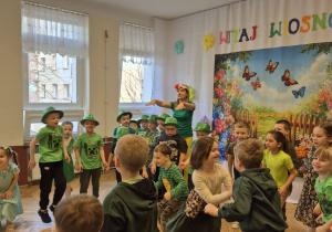 tańczace pzrredszkoalki i nauczycielka w zielonych, wiosennych strojach