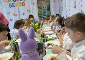 grupka przedszkolaków, stół z wielkanocnymi potrawami