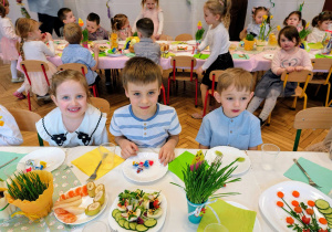 grupka przedszkolaków, stół z wielkanocnymi potrawami
