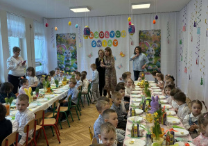 grupka przedszkolaków, nauczycielki, stół z wielkanocnymi potrawami