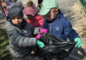 przedszkolaki na dworze, z workiem na śmieci w rękach