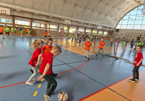 szkolna sala gimnastyczna, przedszkolaki grające w piłkę nożną