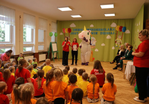 grupa przedszkolaków, osoby dorosłe, osoba w przebraniu jednorożca na tle dekoracji na Dzień Przedszkolaka