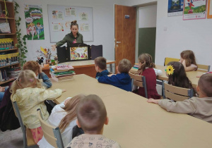 sala biblioteczna, przedszkolaki przy stolikach, oglądanie teatrzyku kamishibai