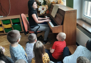 dzieci słuchają grającej na pianinie nauczycielki