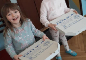 dwie dziewczynki niosące pudełka z pizzą