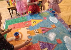 Dzieci malują zamek farbami.