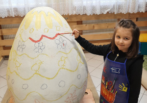 Hania maluje wzór na jajku.