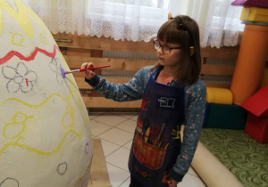 Amelka maluje jajko.