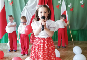 dziewczynka z mikrofonem na tle symboli narodowych