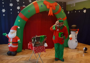 magik w przebraniu elfa na tle świątecznej dekoracji