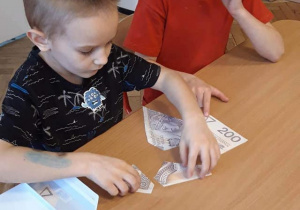 chłopcy układający puzzle przedsztawiające banknoty