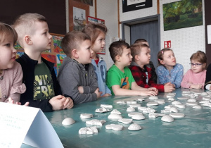 grupka dzieci, figurki gipsowe leżące na stole