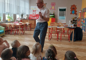 mężczyzna z flagą Polski i grupka dzieci siedząca tyłem