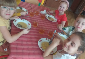 dzieci siedzące przy stolikach jedzące obiad