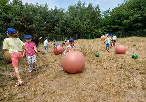 dzieci turlające wielkie piłki