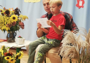 chłopiec na kolanach taty czytającego wiersz