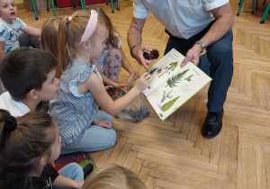 mężczyzna pokazujący dzieciom atlas roślin