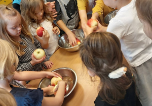 dzieci sięgające po jabłka