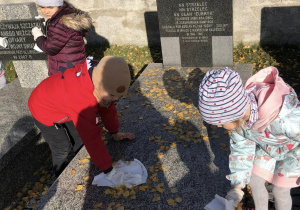 dzieci porządkujące grób żołnierza