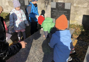 dzieci porządkujące grób żołnierza
