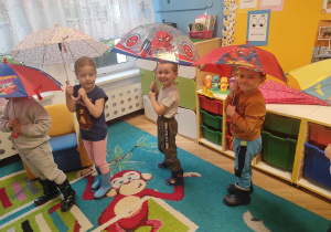 dzieci w sali przedszkolnej pod parasolkami